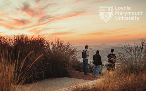 Students sitting near the bluff in contemplation. There is a sunset over the Pacific Ocean Skyline.